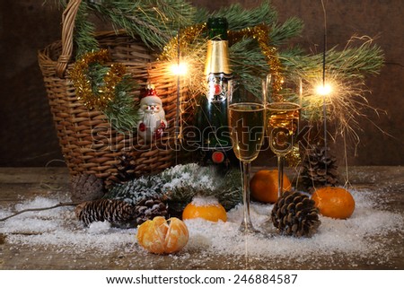 Champagne, tangerines, Bengal fire and fur-tree branch with cones under snow