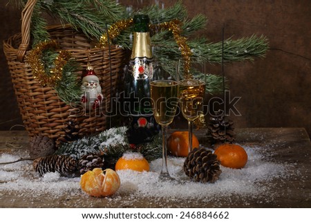 Champagne, tangerines and fur-tree branch with cones under snow