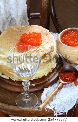 Pancakes submitted with red caviar and white wine, caviar in a wooden bowl