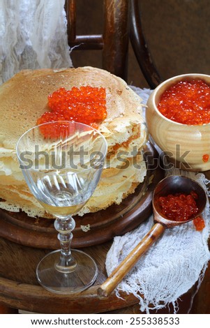 Pancakes submitted with red caviar and white wine, caviar in a wooden bowl