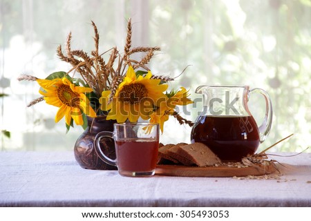 kvass (kvas) in a transparent jug and a bouquet of sunflowers