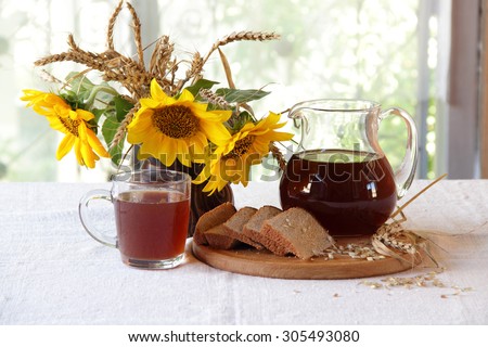 kvass (kvas) on rye ferment, bread and a bouquet of sunflowers