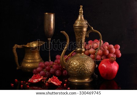 Still-life in east style with pink grapes, a pomegranate and a copper jug