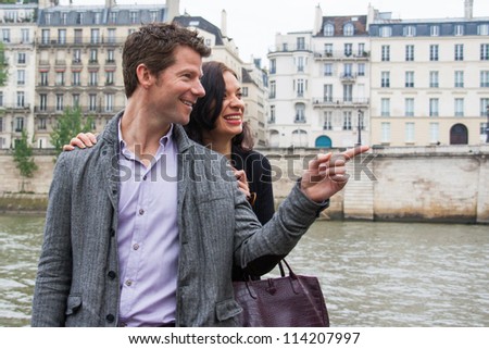 A man pointing to something, while a woman looks on and laughs.