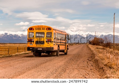 Mountain Valley, Colorado, USA, April 4, 2014. Yellow school bus on a country road with the  Rocky Mountains in the background.