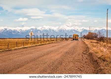 Mountain Valley, Colorado, USA, April 4, 2014. Yellow school bus on a country road with the Rocky Mountains in the background