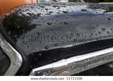Water drops on black car surface.