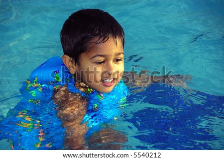 An young indian boy having fun swimming in the pool