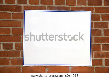 A blank white sign board against a brick wall ready for your text
