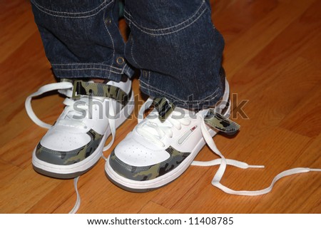 A pair of untied shoes on a toddler\'s legs