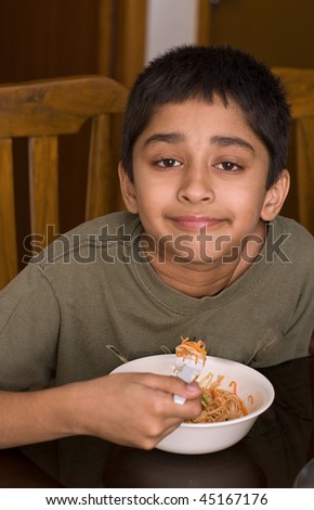 Handsome Indian kid happy eating noodles
