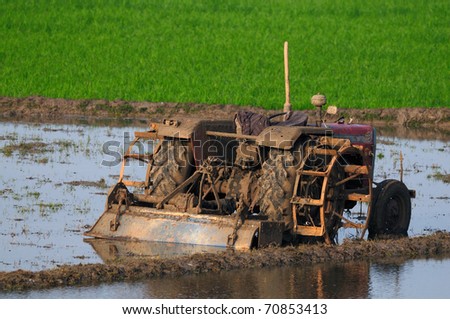 agricultural land being ploughed using an old tractor in modern india
