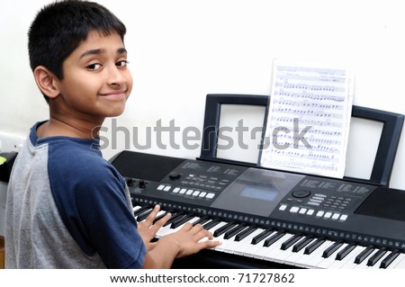 An handsome Indian boy learning music with an electric piano