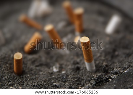 Cigarette butts, many, in ashtray with gray sand, in an outside public area