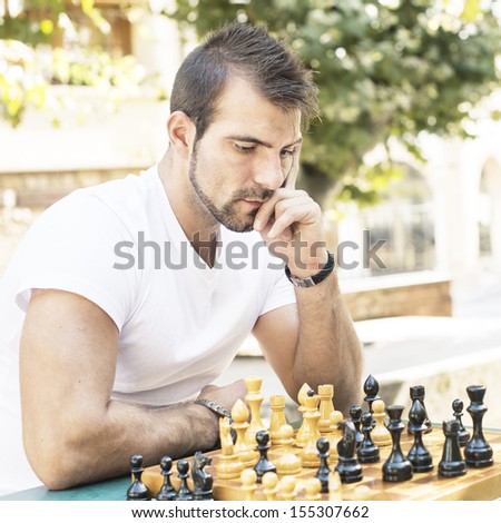 Pensive man plays chess in the park.