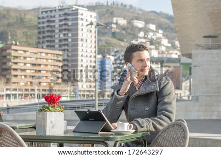 Man laptop computer and talking by phone in public space.