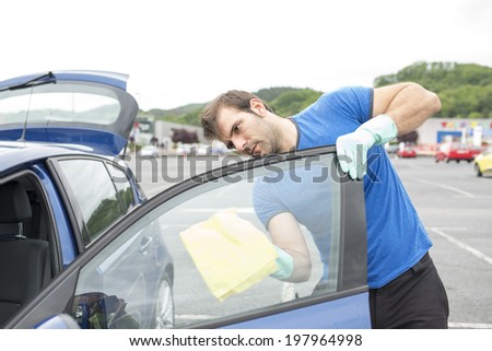 Man cleaning car glass with sponge.