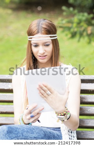Young beautiful woman looking message in tablet computer, outdoor.