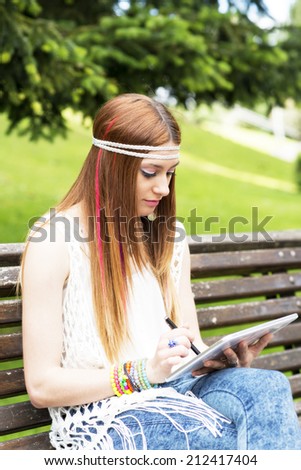 Young hippie girl laptop tablet computer in the park.