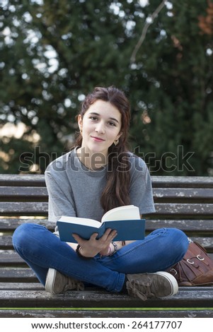 Happiness student sitting on old wood bench in the park with blue book.