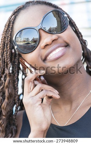 Closeup portrait of beautiful smiling african young woman with sunglasses talking by cellphone.