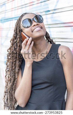 Portrait of beautiful elegant african young woman with sunglasses talking by cellphone, urban style.