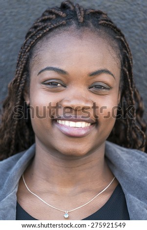 Closeup portrait of smiling beautiful african young woman on gray background, feeling and emotion concept.