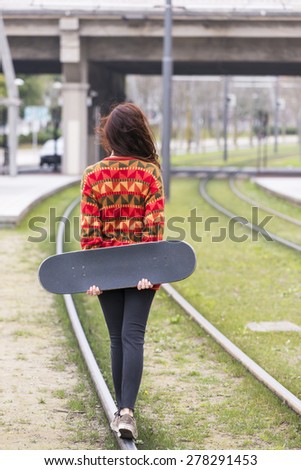 Young hipster woman walks by old rail in the street, adolescence lifestyle concept.