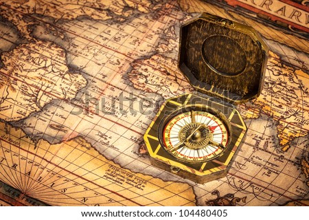 Vintage pirate retro compass on ancient world map. The map used for background is in Public domain. Map source: Library of Congress. Country: Belgium Year: 1570. Author: Abraham Ortelius (1527-1598)