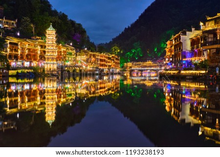 Chinese tourist attraction destination - Feng Huang Ancient Town (Phoenix Ancient Town) on Tuo Jiang River illuminated at night. Hunan Province, China