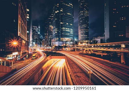 Street traffic in Hong Kong at night. Office skyscraper buildings and busy traffic on highway road with blurred cars light trails. Hong Kong, China