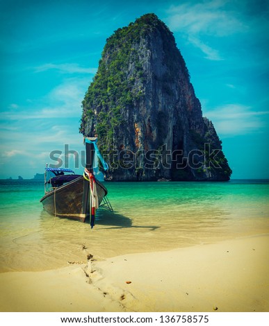 Long tail boat on tropical beach with limestone rock, Krabi, Thailand. Vintage style, cross process