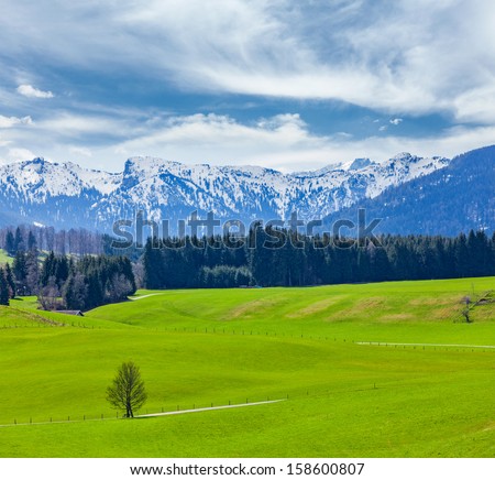 German idyllic pastoral countryside in spring with Alps in background. Bavaria, Germany