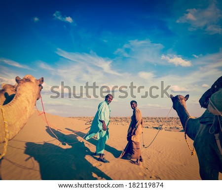 Vintage retro hipster style travel image ofvintage retro hipster style travel image of Rajasthan travel background - two indian cameleers (camel drivers) with camels.  Thar desert,  Rajasthan, India