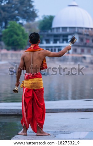 UJJAIN, INDIA - APRIL 23, 2011: Brahmin performing Aarti pooja ceremony on bank of holy river Kshipra. Aarti is Hindu religious ritual of worship part of puja when light offered to one or more deities
