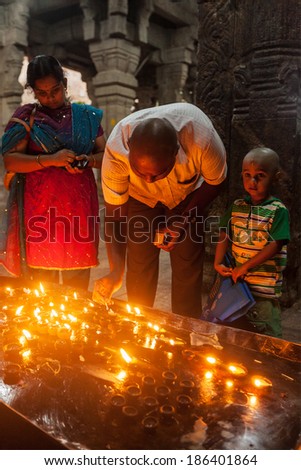 TIRUCHIRAPALLI, INDIA - FEBRUARY 14, 2013: Unidentified Indian family father mother son worshipping by lighting ghee lamps in Hindu tempe Sri Ranganathaswamy Temple