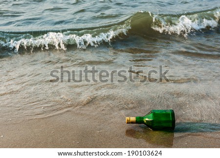 Message bottle on beach sand in waves