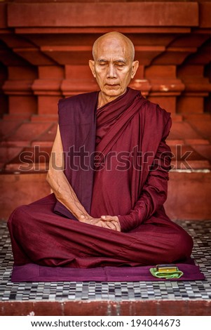YANGON, MYANMAR - JANUARY 3, 2014: Ascetic Buddhist monk meditating in Shwedagon Paya pagoda. Buddhism is major religion of Myanmar and belongs to Theravada branch