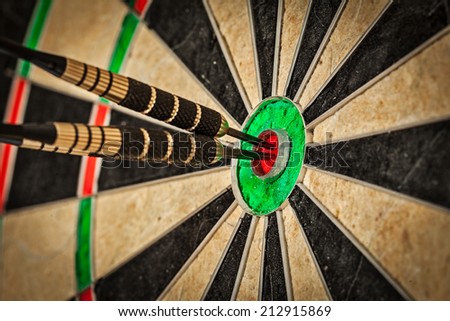 Success hitting target aim goal achievement concept background - three darts in bull\'s eye close up