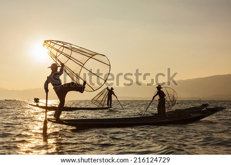 Myanmar travel attraction landmark - three traditional Burmese fishermen at Inle lake, Myanmar famous for their distinctive one legged rowing style
