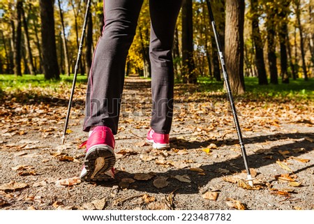 Nordic walking: adventure and exercising concept - woman hiking, legs and nordic walking poles in autumn nature