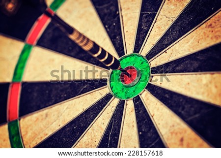 Vintage retro effect filtered hipster style image of   -Success hitting target aim goal achievement concept background - dart in bull\'s eye close up