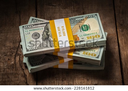 Creative business finance making money concept - stacks of new 100 US dollars 2013 edition banknotes (bills) bundles isolated on wooden background