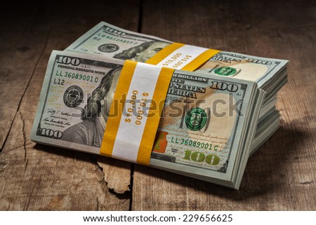 Creative business finance making money concept - stacks of new 100 US dollars 2013 edition banknotes (bills) bundles isolated on wooden background