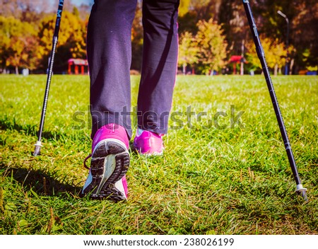 Vintage retro effect filtered hipster style image of nordic walking adventure and exercising concept - woman hiking, legs and nordic walking poles in summer nature