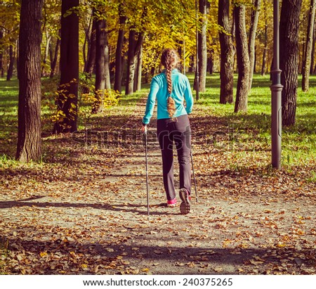 Vintage retro effect filtered hipster style image of nordic walking adventure and exercising concept - woman hiking with nordic walking poles in park