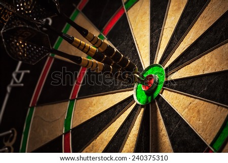 Success hitting target aim goal achievement concept background - three darts in bull\'s eye close up