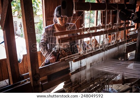 INLE LAKE, MYANMAR - JANUARY 8, 2014: Burmese woman weaves fabric at weaving factory where textile is manufactured in traditional way
