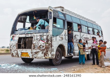 MADHYA PRADESH, INDIA - APRIL 12, 2011: Indian bus driver cleaning shattered windshield glass after traffic accident. The rate of traffic accidents in India is amongst the highest in the world