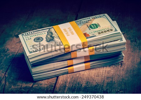 Creative business finance making money concept - Vintage retro effect filtered hipster style image of stacks of new 100 US dollars 2013 edition banknotes (bills) bundles isolated on wooden background